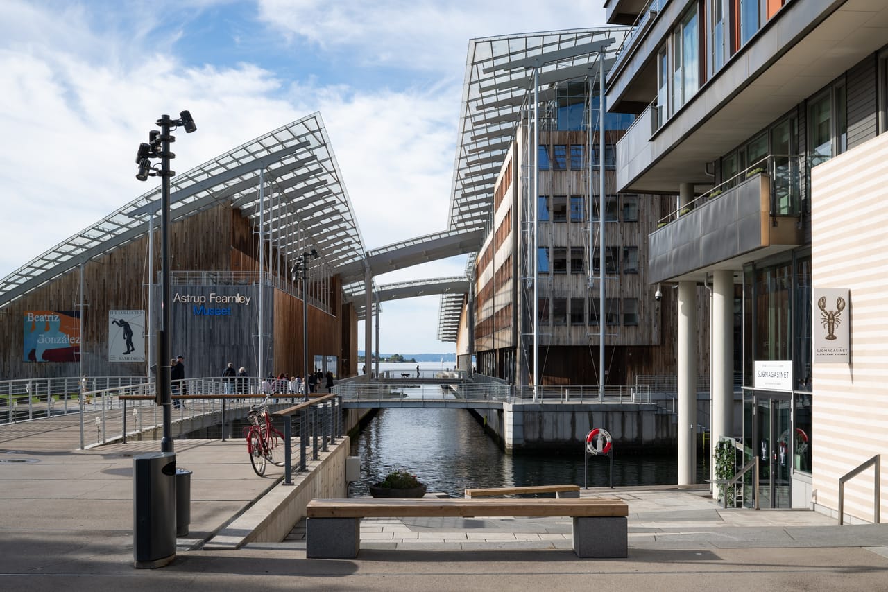 Astrup Fearnley-museet sett fra kanalsiden, med det skråstilte glasstaket og en sykkel parkert ved rekkverket.