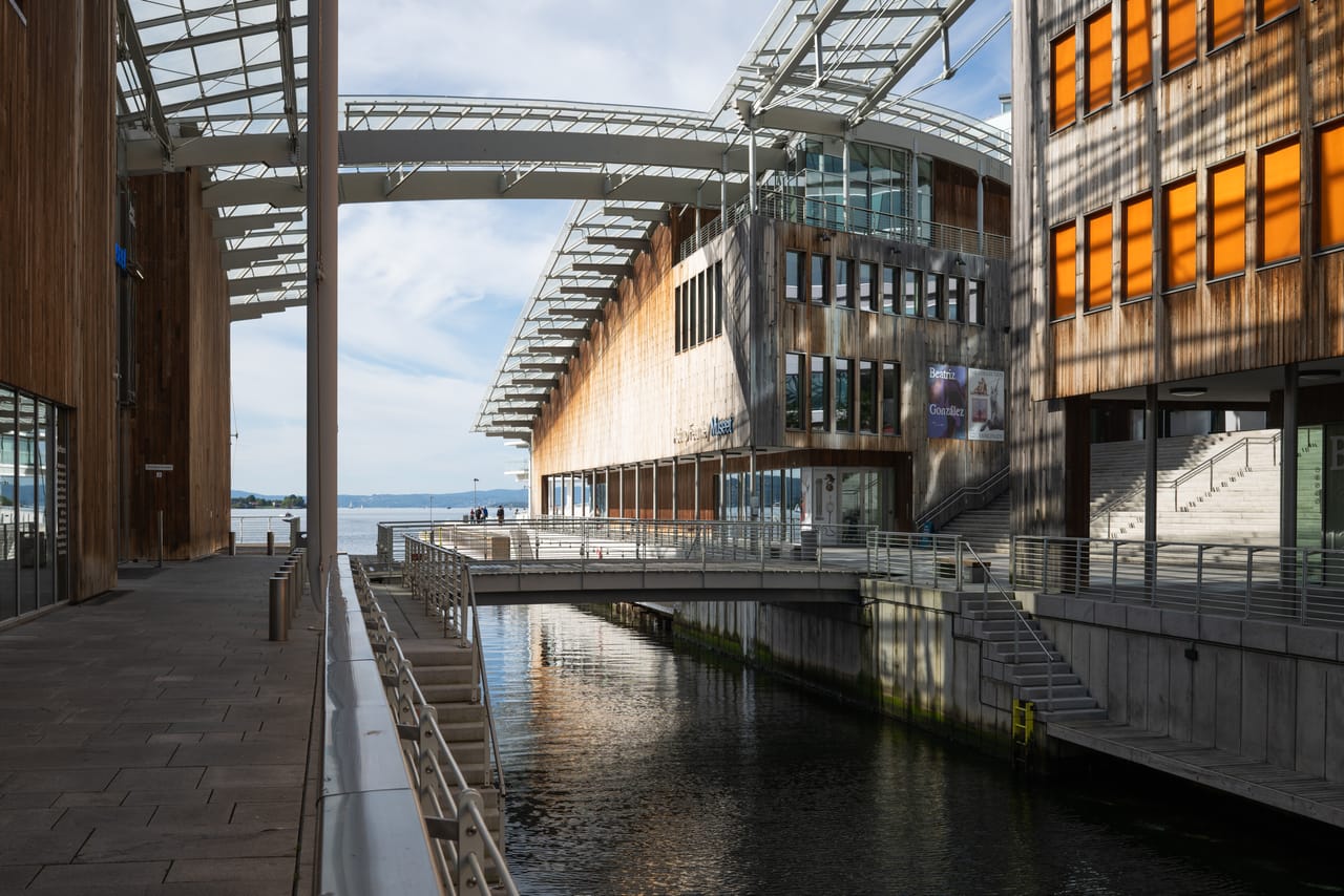 Astrup Fearnley-museet fra en annen vinkel, med trekledningen i lavt sollys og glasstaket som strekker seg mellom bygningene.